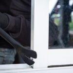 Inbreker met handschoenen probeert raam open te breken met koevoet, woningbeveiliging in actie